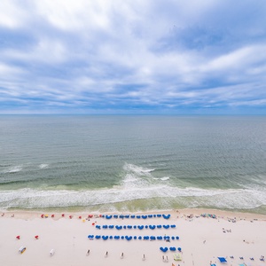 Expansive views of the pristine beach lined with colorful umbrellas and loungers under a serene sky