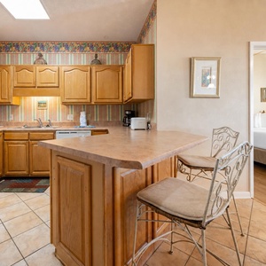 Wooden cabinetry complements the inviting breakfast bar, creating a welcoming space for casual meals and gatherings