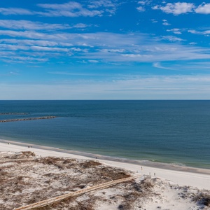 Stunning view of the tranquil beach, gulf waters, and soft white sand stretching along the shoreline to the jetties