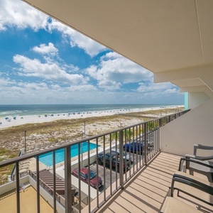 Enjoy expansive views from the balcony overlooking the pristine beach and inviting pool area, perfect for relaxation