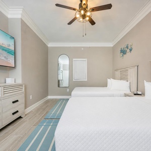 Relax in this inviting guest room featuring two queen beds, a large TV, and coastal decor for a refreshing stay