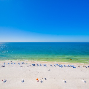 Relax as sparkling blue water stretches to meet the horizon under a clear sky on this bright day