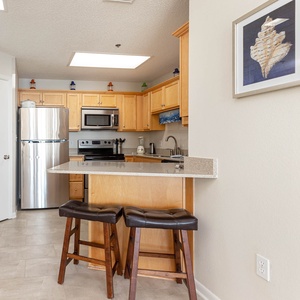 Bright wooden cabinetry complements the kitchen's sleek appliances and inviting breakfast bar with stylish seating