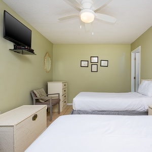 This guest bedroom features two beds, a mounted TV, and charming decor, creating a relaxing retreat for visitors