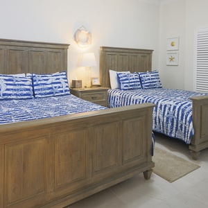 Unwind in this guest suite with two plush queen beds, soft lighting, and charming coastal decor