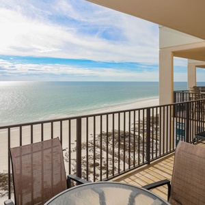 Savor the serene views from the balcony, featuring comfortable seating and a table for enjoying drinks outdoors