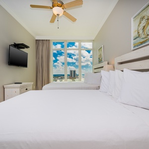 Relax in this guest bedroom with two queen beds and large windows framing beautiful views of the beach