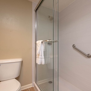 Walk-in shower with glass enclosure with plush towels in the master bath, complemented by neutral walls and tiles