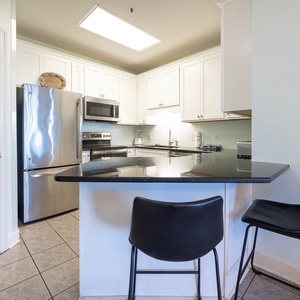 Kitchen features sleek black countertops, stainless appliances, and a breakfast bar with stylish seating for casual dining