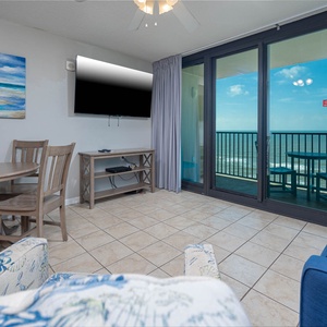 Relax in the inviting living area with a flat-screen TV, dining table, and stunning views from the beachfront balcony