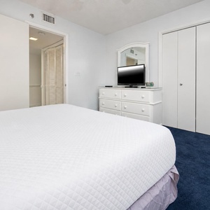 Guest bedroom featuring a cozy queen bed, a dresser with a TV, and ample closet space for a comfortable stay