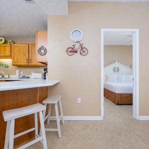 Bright kitchen with breakfast bar stools opens to the calm master suite where you rest after a day by the shore