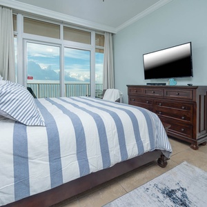 Enjoy a restful night in the master bedroom with a king bed, large TV, and beach views from the balcony