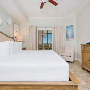 Relaxing master bedroom featuring a plush king bed, a cozy armchair, and a view of the serene coastline