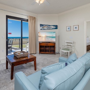 Relax in the airy living room, featuring comfortable seating and views of the outdoor patio area and beach beyond