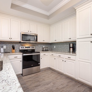 Prepare meals in this kitchen with elegant cabinetry, stainless appliances, and stylish backsplash