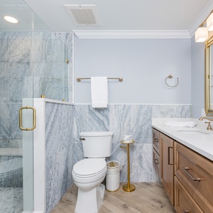 Indulge in a refreshing shower under the elegant rainfall showerhead, surrounded by stylish accents in this master bath