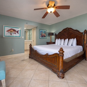 The master bedroom features a beautifully carved wooden king bed, vibrant artwork, and a stylish lamp, perfect for relaxation