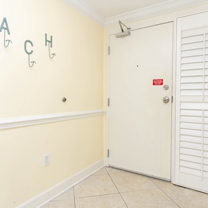 Welcoming entryway features a light yellow wall, decorative hooks spelling 