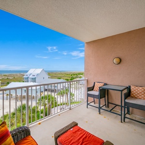 Enjoy a stunning beach view from this balcony, featuring a telescope and a sleek table with chairs for relaxation