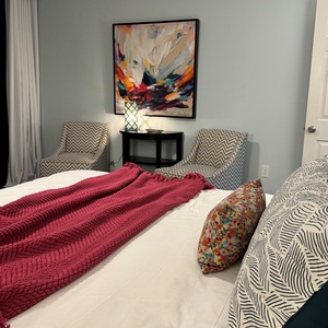 Relax in the inviting master bedroom with a king bed, colorful throw, and cozy chairs for a peaceful retreat