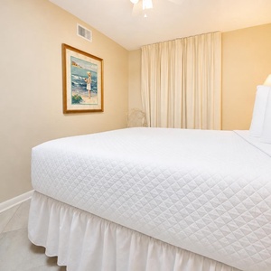 Relax in this inviting guest bedroom featuring a queen bed, soft lighting, and charming art
