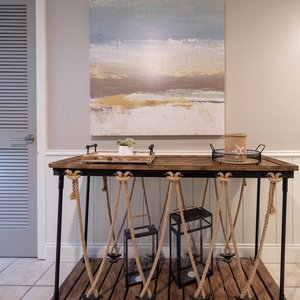 A rustic console table with rope accents holds decorative items and a small plant, enhancing the welcoming entryway vibe