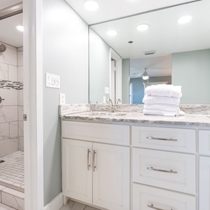 Experience a stylish master bathroom featuring a spacious walk-in shower, elegant countertops, and fresh towels