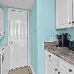 Kitchen corner featuring a coffee maker, toaster, and laundry area with a cheerful blue accent wall
