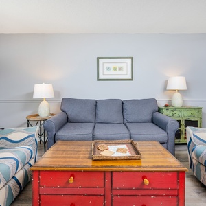 Relax in the inviting living area with comfortable seating, a rustic coffee table, and charming coastal decor