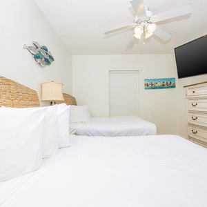 Sleep comfortably in this cozy guest bedroom with two queen beds, a ceiling fan, and beach decor to enhance your stay