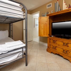 Full bunk bed with fresh linens complements a wooden entertainment unit featuring a TV, creating a cozy retreat for guests