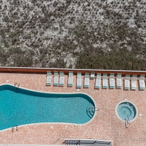The pool area features a sparkling blue pool and a relaxing hot tub surrounded by lounge chairs, perfect for sunbathing