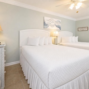 Rest in this guest room featuring two queen beds, coastal decor, and a charming lamp for a cozy ambiance
