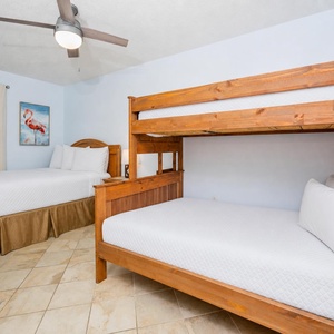 Cozy guest bedroom features a double bed and a wooden twin over double bunk bed, complemented by light blue walls