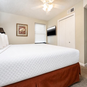 Experience restful nights in the king suite with a cozy bed, soft lighting, and a mounted TV