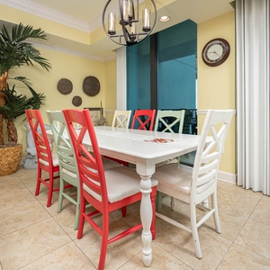 Gather around the colorful dining table, surrounded by tropical decor and large windows for a refreshing view