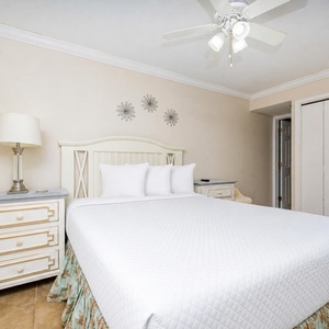 Cozy guest bedroom featuring a queen bed with white linens, a decorative headboard, and stylish bedside tables