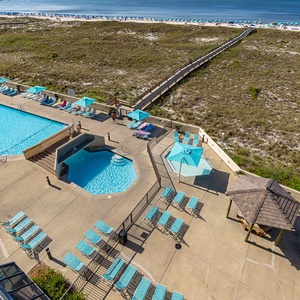 Cool pool water shimmers as you lounge nearby under umbrellas beside the calm beach access path