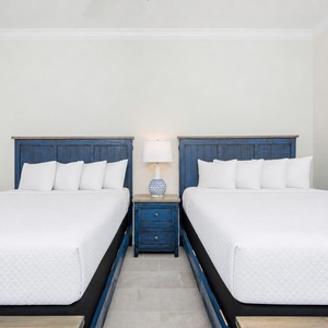 Rest in this guest bedroom featuring two queen beds, stylish headboards, and a coastal vibe