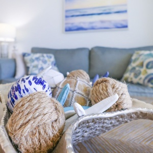 The living area features a blue sofa, decorative pillows, and stylish centerpiece with nautical decor, perfect for relaxation