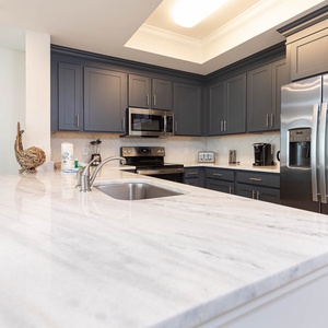 Brew your morning coffee at the marbled counter in this stylish kitchen with elegant cabinetry