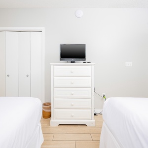 Serene guest bedroom featuring two double beds, a TV, and soft tones that create a calming atmosphere