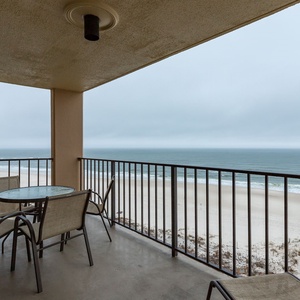 This balcony offers a relaxing space with a table and chairs, perfect for enjoying the serene beach view