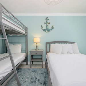 Guest bedroom featuring a gray twin bunk bed and a full bed, accented by a soft blue wall and nautical decor