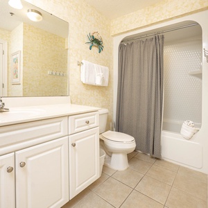 Refresh in this guest bathroom featuring a spacious vanity, a relaxing tub/shower, and cheerful coastal decor