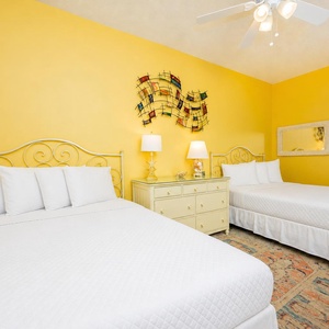 Experience comfort in this guest bedroom with two queen beds, bright yellow walls, and playful decor