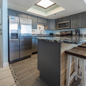 Kitchen featuring stainless appliances, granite countertops, and rustic bar stools for casual dining