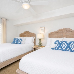 Bright guest bedroom featuring two double beds, soft linens, and coastal decor for a relaxing getaway