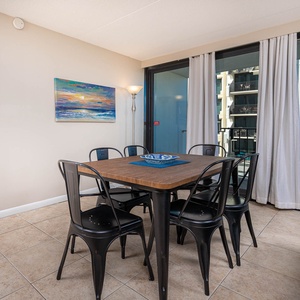 The dining area features a stylish table surrounded by black chairs, with a view of the balcony through large glass doors